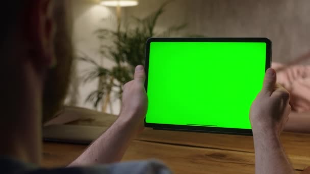 Câmera de mão: Sobre o ombro Ver Jovem em casa usando com Green Mock-up Screen Tablet. Assistir conteúdo sem tocar tela Gadget. Navegação Internet. — Vídeo de Stock