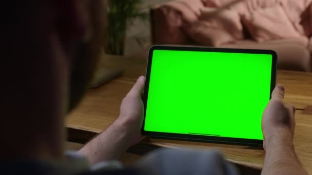 Cámara portátil: sobre el hombro Ver joven en casa usando con Green Mock-up Screen Tablet. Ver contenido sin tocar la pantalla del gadget. Navegar por Internet. — Vídeos de Stock