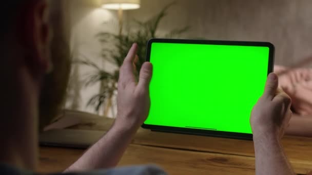 Φορητή κάμερα: Πάνω από το Shoulder View Man Χρησιμοποιώντας χειρονομίες χέρι σε πράσινο mock-up οθόνη Ψηφιακός υπολογιστής tablet σε λειτουργία τοπίου. Πατώντας στην κεντρική οθόνη — Αρχείο Βίντεο