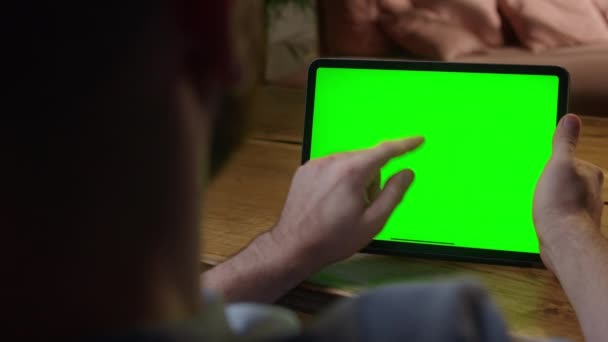 手持ちカメラ:緑のモックアップ画面上の手のジェスチャーを使用して肩のビューの男の上に風景モードでデジタルタブレットコンピュータ.センター画面をタップする — ストック動画