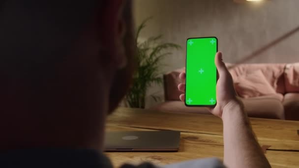 Φορητή κάμερα: Πίσω όψη του ανθρώπου στο τηλέφωνο με πράσινη οθόνη για αντίγραφο χώρου. Chromakey Mock Up Χωρίς Ανίχνευση Δείκτες. Πατήστε για να κάνετε κλικ στο κέντρο της οθόνης — Αρχείο Βίντεο