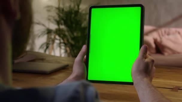 Cámara portátil: sobre el hombro Ver joven en casa usando con Green Mock-up Screen Tablet. Ver contenido sin tocar la pantalla del gadget. Navegar por Internet. — Vídeo de stock