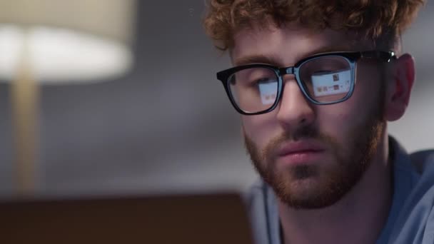 夜に働く男の肖像モニターを見ると、眼鏡の反射。眼鏡の男性の目夜遅くノートパソコンの前でスクロールします。Internet Web Surfing — ストック動画