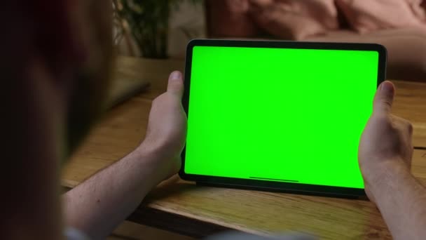 Cámara portátil: sobre el hombro Ver joven en casa usando con Green Mock-up Screen Tablet. Ver contenido sin tocar la pantalla del gadget. Navegar por Internet. — Vídeos de Stock