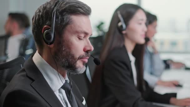 Close-up Portret van een specialist in technische klantenservice die 24 uur per dag met een headset praat tijdens het werken aan een computer in het callcenter en behulpzame klantenservice. — Stockvideo