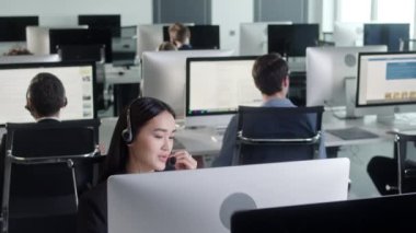 Bir çağrı merkezinde bilgisayar üzerinde çalışırken kulaklıkla konuşan Teknik Müşteri Destek Uzmanının Portresi 'ni Kapat.