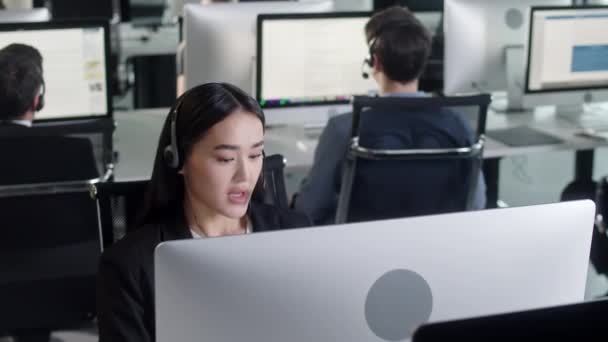 Fermer Portrait de femme Spécialiste du soutien technique à la clientèle Parler sur un casque tout en travaillant sur un ordinateur dans le centre d'appels et un service à la clientèle utile 24 heures sur 24, 7 jours sur 7. — Video