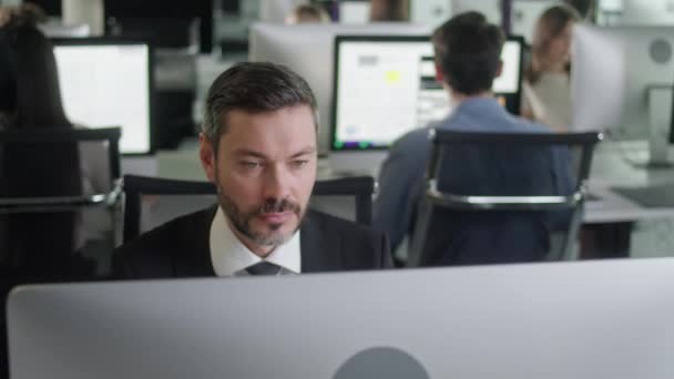 Retrato de un hombre de mediana edad en una oficina de espacio abierto que trabaja en un ordenador de decadencia. Mecanografía profesional masculina en el teclado de PC. Retrato del hombre de negocios positivo mirando la pantalla de la computadora — Vídeos de Stock