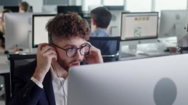 Çağrı merkezinde bir bilgisayar ve 7 / 24 yardımcı müşteri hizmetleri üzerinde çalışırken kulaklıkla konuşan bir teknik müşteri destek uzmanının portresi. Bilgisayar tablosu ve telefon hattında masaüstü bilgisayarı kullan
