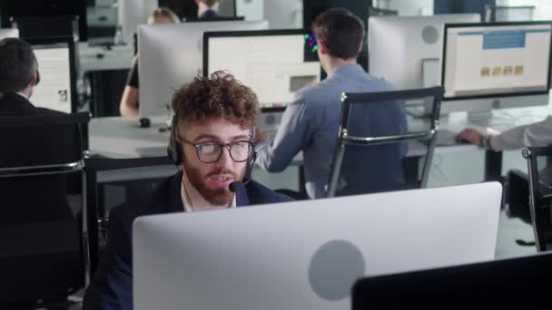 Retrato de un especialista en atención al cliente técnico Hablando con auriculares mientras trabaja en una computadora en el centro de llamadas y un servicio al cliente útil las 24 horas, los 7 días de la semana. Utilice la PC de escritorio en la mesa de la computadora y la línea telefónica — Vídeos de Stock