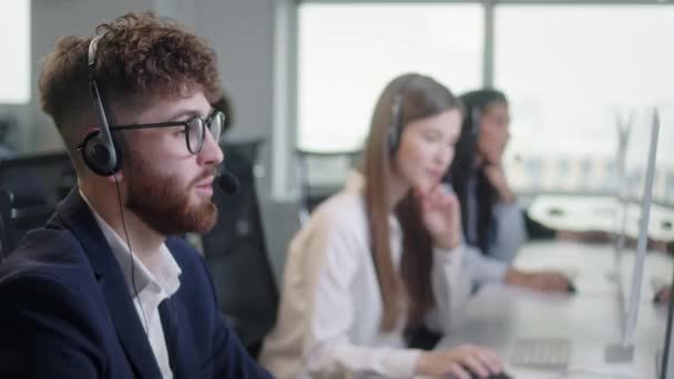 Retrato de um especialista técnico em suporte ao cliente conversando em um fone de ouvido enquanto trabalhava em um computador em call center e serviço ao cliente útil 24-7. Use PC desktop na mesa do computador e linha telefônica — Vídeo de Stock