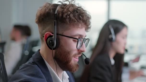 Close Up Portrait eines technischen Kundendienstspezialisten, der an einem Headset spricht, während er im Call Center an einem Computer arbeitet und 24-7 Stunden für den Kundendienst arbeitet. — Stockvideo