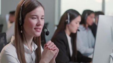 Çağrı merkezinde bir bilgisayar ve 7 / 24 yardımcı müşteri hizmetleri üzerinde çalışırken Kulaklıkla konuşan Teknik Müşteri Destek Uzmanı Bir Kadının Portresini Kapat.