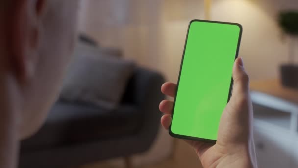 Back View of Man Holding Chroma Key Green Screen Smartphone Watching Content Without Touching or Swiping. Boy Using Mobile Phone, Browsing Internet, Sledování obsahu, Videa, Blogy. — Stock video