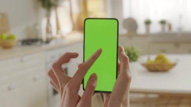 Mutfak Odasında Yeşil Model Ekran Kroma Anahtarı ile Telefon Kullanan Bir Kadın Görünümü İnternet İzleme İçerik Videoları bloglarında geziniyor. Orta Ekranda Tıklama