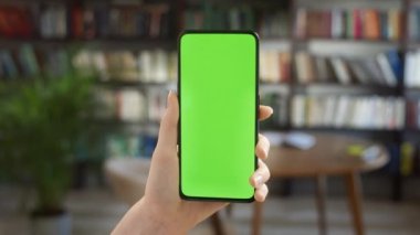Dokunmadan Yeşil Ekran. Merkez Ofis veya Kütüphane İzleme İçeriğinde Kroma Anahtar Yeşil Ekran Telefonu Tutan Kadın Bakış Açısı. İnternet taraması, İçerik İzleme, Videolar, Bloglar.