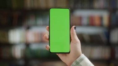Dokunmadan Yeşil Ekran. Merkez Ofis 'te ya da Kütüphane İzleme İçeriğinde Krom Anahtarlı Yeşil Ekran Telefonu Tutan Bakış Açısı. İnternet taraması, İçerik İzleme, Videolar, Bloglar.