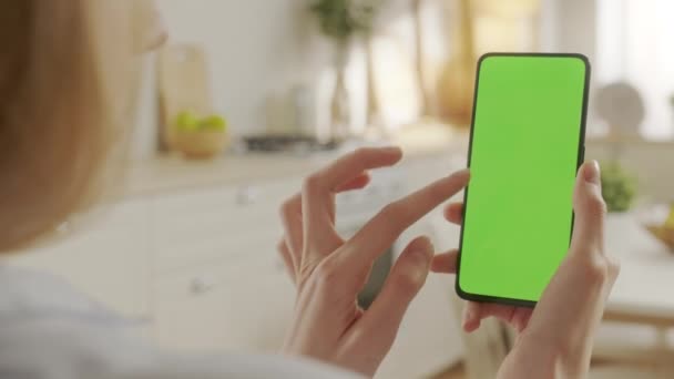 Зворотній перегляд жінки на кухні з використанням телефону з зеленим макетним екраном Chroma Key без точок доріжки Серфінг Інтернет Перегляд контенту Відео Блоги. Натискання на центральний екран — стокове відео