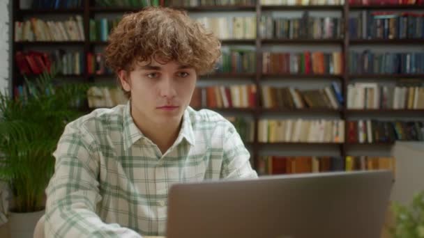 Hombre de estudiante atractivo mirando el monitor de computadora portátil haciendo investigación. Joven Hombre Profesional Usando Ordenador Sentado en la Oficina del Hogar o Biblioteca. Trabajador ocupado Freelancer Trabajar — Vídeos de Stock