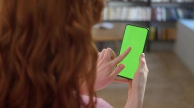 Ekran Merkezine Tıklayın. Uzayı Kopyalamak için Yeşil Ekranlı Telefondaki Kadın Görünümü. Chromakey İşaretlemesiz Mock Up. 20 'li yaşlarda Kanepe' de Video Haberleri İzleyen Kız.