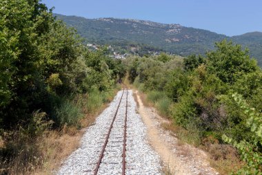 Güneşli bir yaz gününde dağlardaki (Yunanistan, Pelion) turist, eski, demiryolu rayları