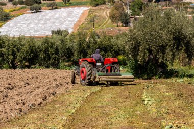 Tarım. Çiftlik arazisi ve traktör güneşli bir bahar gününde uzak mesafede çalışıyor.