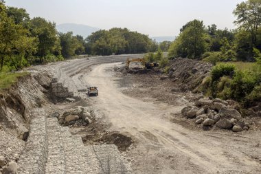 Güneşli bir sonbahar gününde nehrin kıyılarını kaldırım taşları ve tellerle güçlendirme çalışmaları (Yunanistan, Orta Makedonya)