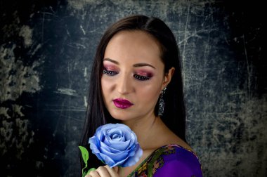 Noel ve Yeni Yıl. Elinde suni mavi gül olan çekici genç bir kızın portresi. Karanlık bir arka planda.