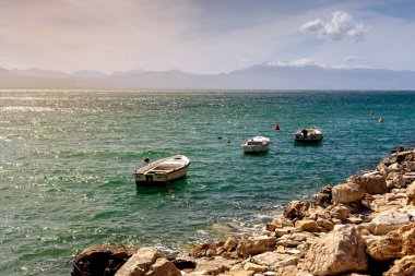 Güneşli bir akşamda Loutraki (Yunanistan) şehrinde deniz manzarası ve demirlemiş üç tekne