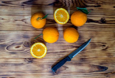 Meyveler. Birkaç taze, olgun portakal ve yakın plan ahşap bir arka planda bir bıçak.
