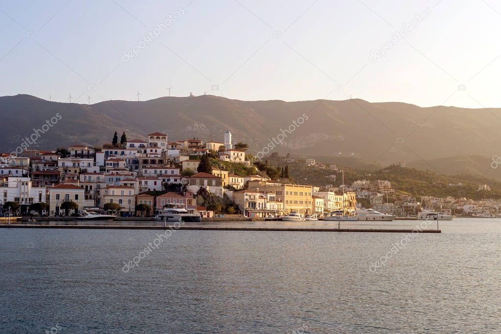 View of the embankment of the island of Poros (Greece), mountains and sea at sunset