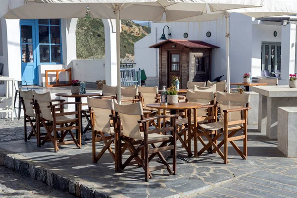 The umbrellas, tables and chairs of a street cafe-restaurant on a sunny spring day (Greece) close-up.