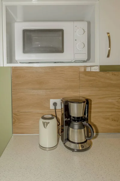 Kitchen equipment. New, large, modern electric kettle, coffee machine and microwave on the kitchen table