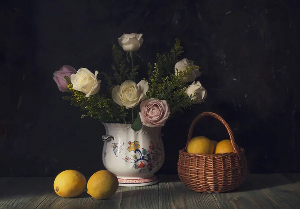 还活着 花瓶里有玫瑰 木制桌子上有一只黄色的柠檬 篮子里有柳条筐 — 图库照片