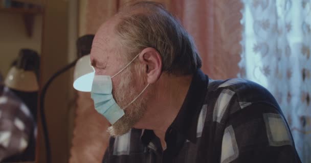 Retrato de anciano solitario llevado en máscara médica mira a la cámara — Vídeo de stock