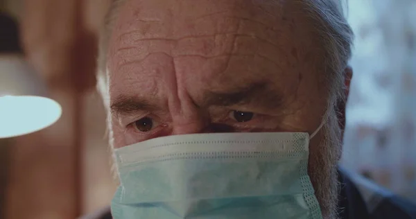 Tıbbi maskeli, terli, üzgün, yaşlı adamın yakın portresi. Telifsiz Stok Fotoğraflar