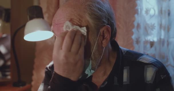 Portrait of sweaty senior man in medical mask wipes his face with a napkin — Stock Video