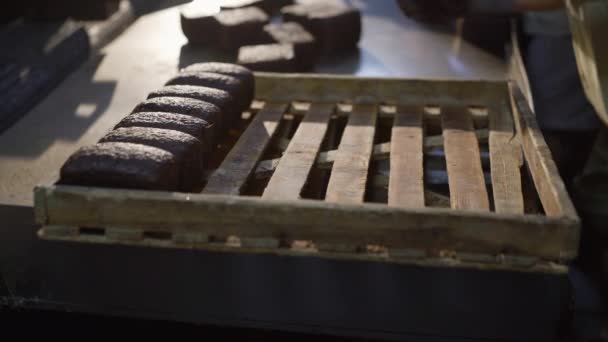 Bäckerhände legen in der Fabrik frisch gebackene Roggenbrote auf ein Blech — Stockvideo