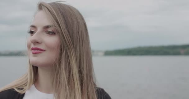 Chica bonita mira a un lado, se regocija en los recuerdos y corrige el cabello en la playa — Vídeo de stock