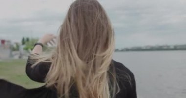 Mutlu kız saçını düzeltir, kameraya döner ve yürürken gülümser.