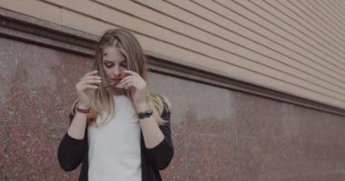 Çekici kız gözlük takıyor, saçlarını düzeltiyor ve bina manzaralı.