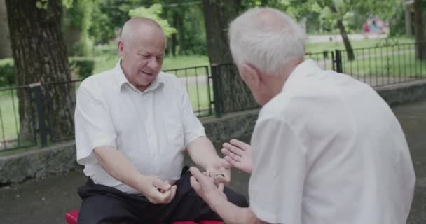 Twee senioren vrienden spelen spel welke hand is schaakstuk in op bank in de zomer — Stockvideo