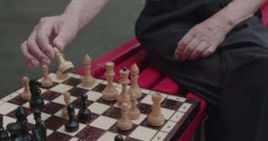 Kıdemli adam boş vakitlerinde arkadaşıyla oynarken satranç oynuyor ve konuşuyor.
