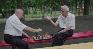 İki iyi son sınıf öğrencisi satranç oynuyorlar, saati kullanıyorlar ve sohbet ediyorlar.