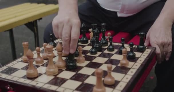 Στενή, χαμηλή άποψη των ηλικιωμένων ανδρών κάνει κινήσεις του σκακιού, ενώ παίζει σε εξωτερικούς χώρους — Αρχείο Βίντεο