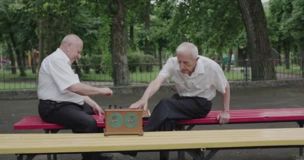 Dos buenos hombres de último año jugando al ajedrez, usando el reloj y teniendo una charla — Vídeo de stock