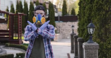 Gözlüklü ve solunum cihazlı virüs uzmanı dışarıdaki kamerada dur işareti gösteriyor.