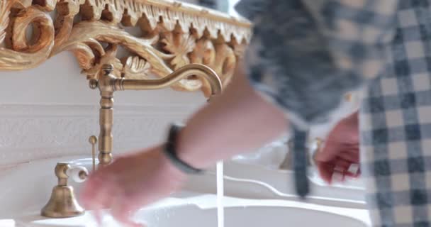 Man wast zijn handen met zeep onder de kraan van een luxe wastafel — Stockvideo