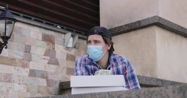 Sorgsen man i medicinsk mask tänker på finansiella intäkter under pandemisk utbrott — Stockvideo