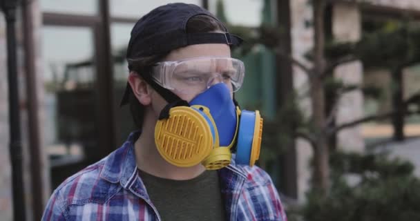 Uomo in occhiali protettivi e respiratore universale guarda fotocamera esterna — Video Stock